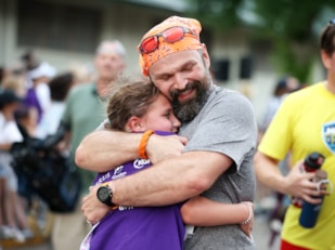 Girls on the Run participant and her 5K buddy smile proudly and hug after completing the 5K