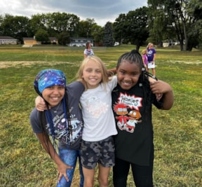 Three Girls on the Run participants wrap their arms around each other and smile