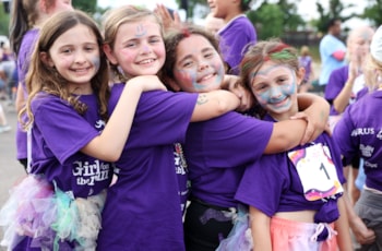 Girls on the Run participants huge and smile in a line on 5K day